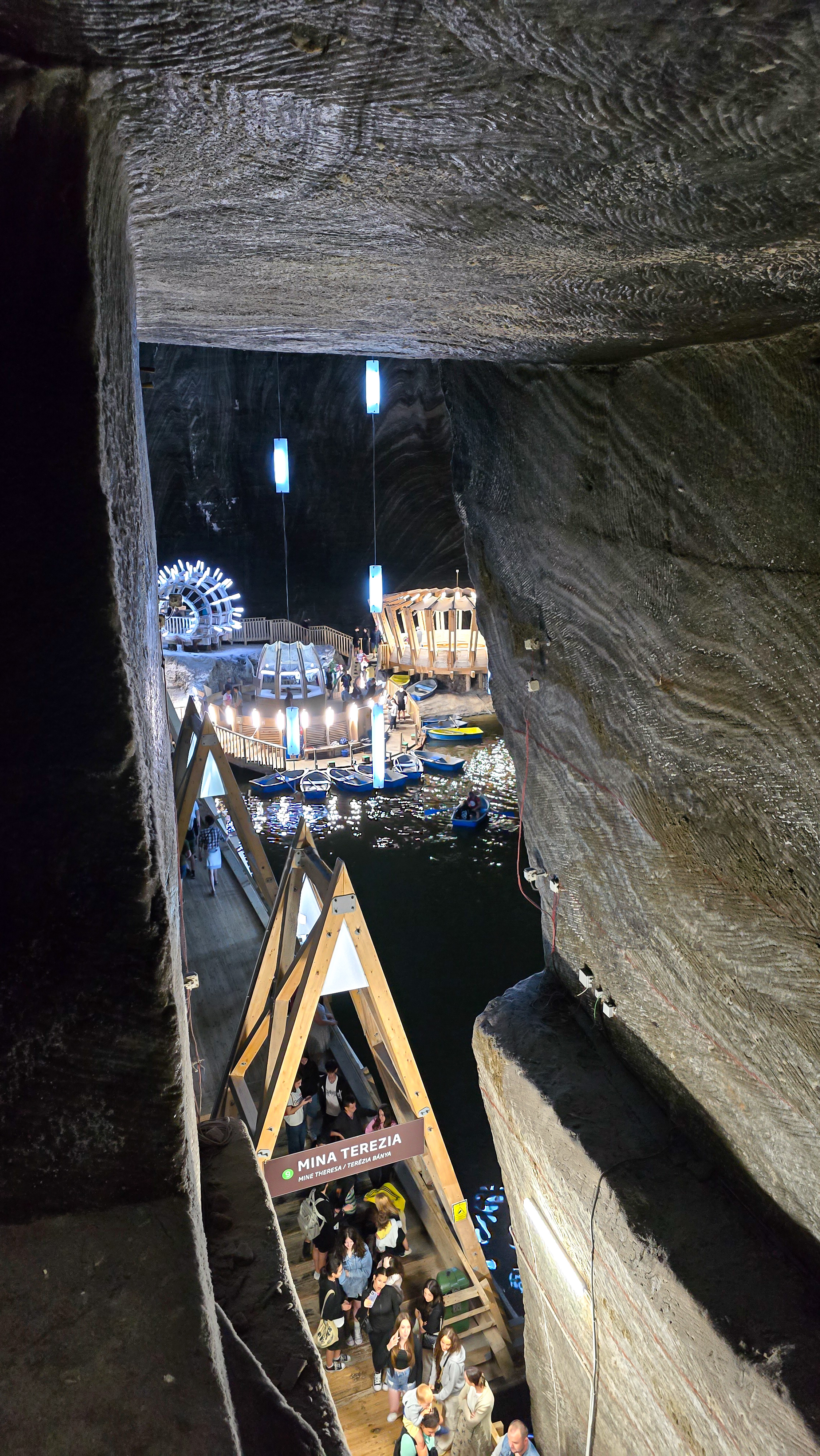 Pohled z okna na schodech v nejnižší části solného dolu Salina Turda, s výhledem na podzemní jezero a solné stěny.